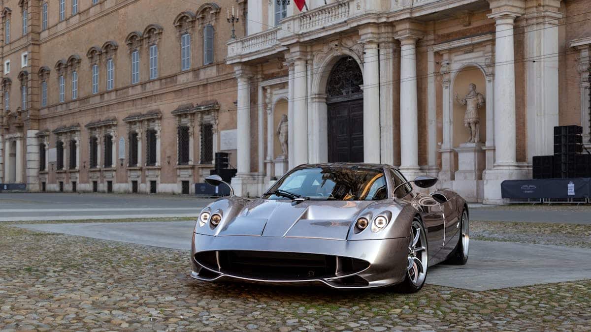 Photograph of a sleek hypercar parked in an elegant historical European courtyard.