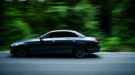 Dynamic shot of a sleek sedan speeding through a lush green forest road in Istanbul.