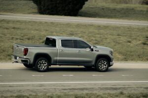 A sleek silver pickup truck in motion on a scenic highway, showcasing modern automotive design.