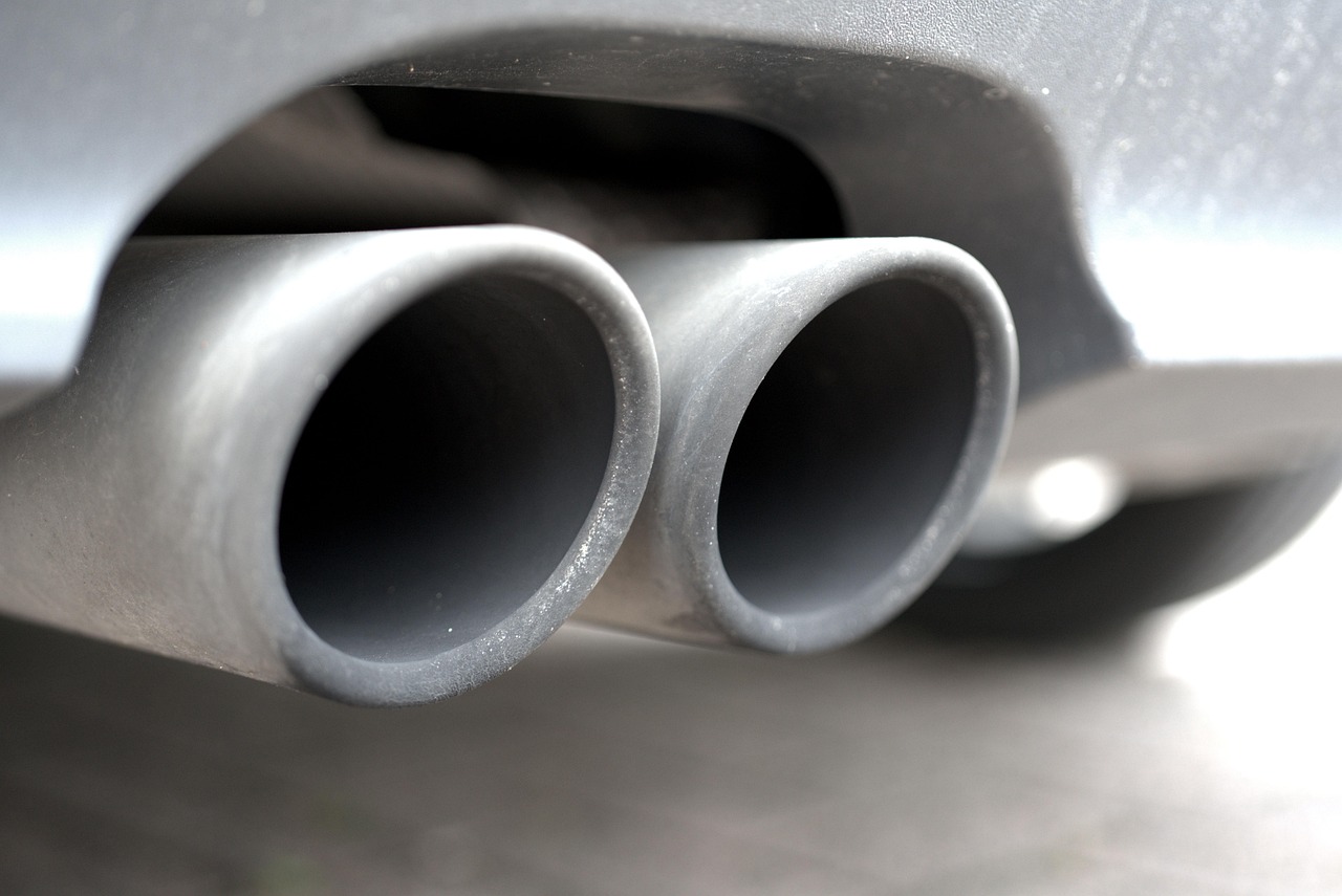 Twin exhaust tailpipes at the rear of a grey car seen up close